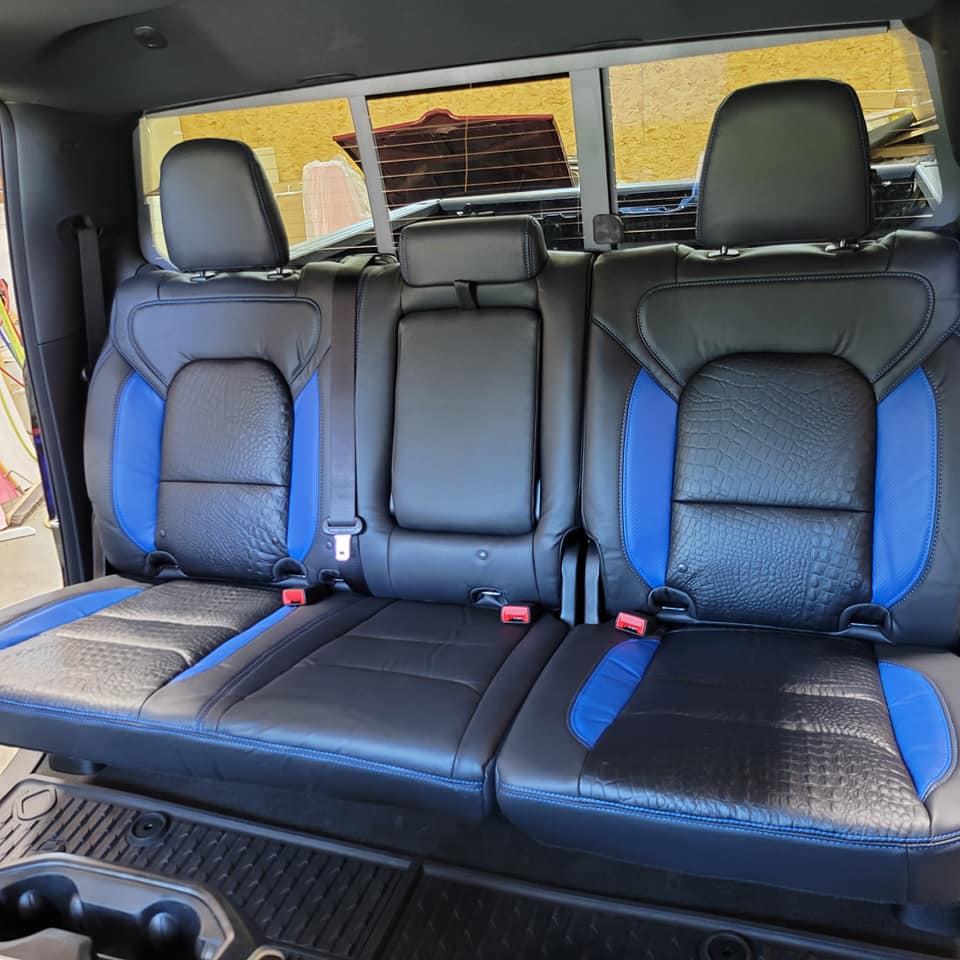 The back seat of a truck with black and blue seats.