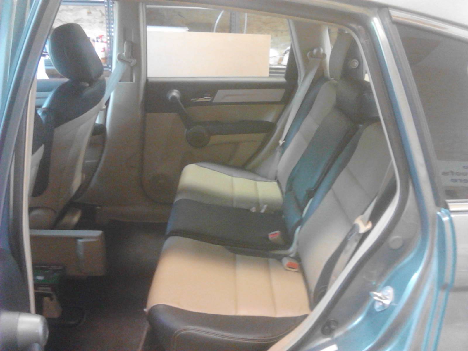 The back seat of a blue car with tan and black seats