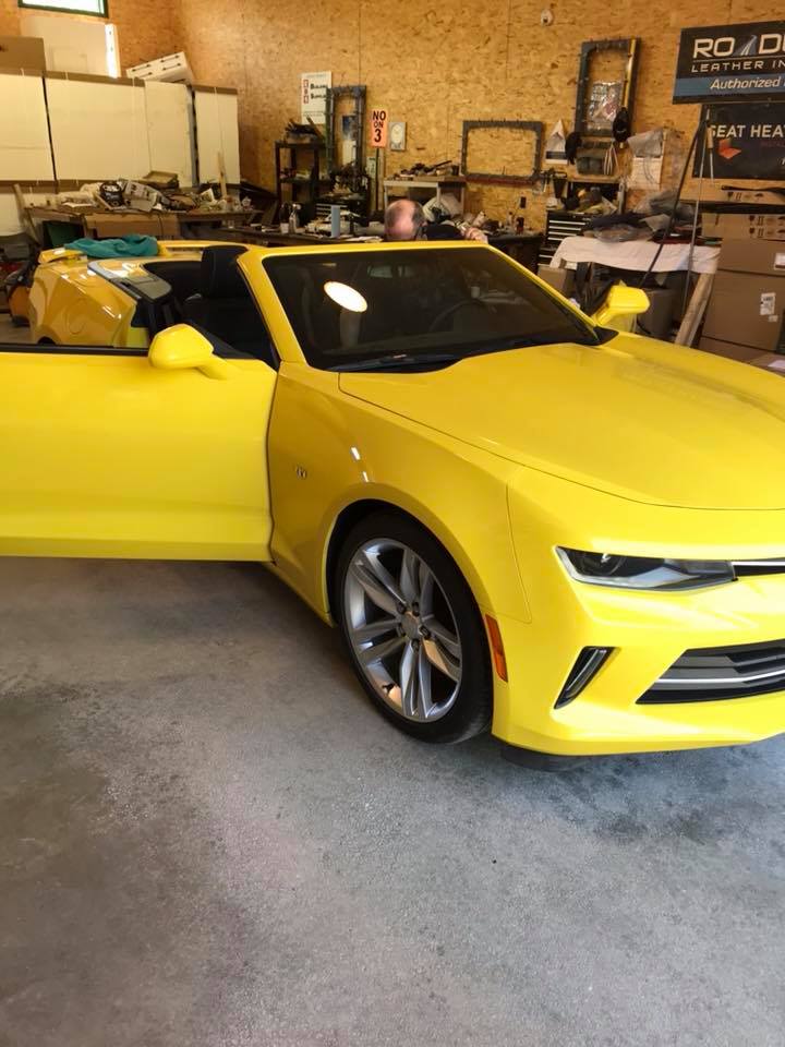 A yellow car is parked in a garage with its doors open.