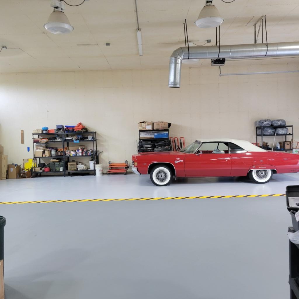 A red car is parked in the middle of a garage