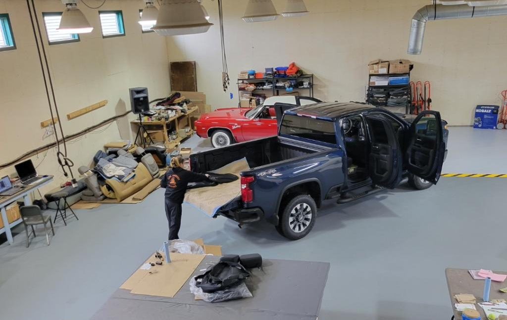 A man is standing next to a truck in a garage.