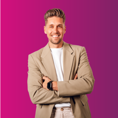 Smiling man in beige blazer with folded arms against a pink background