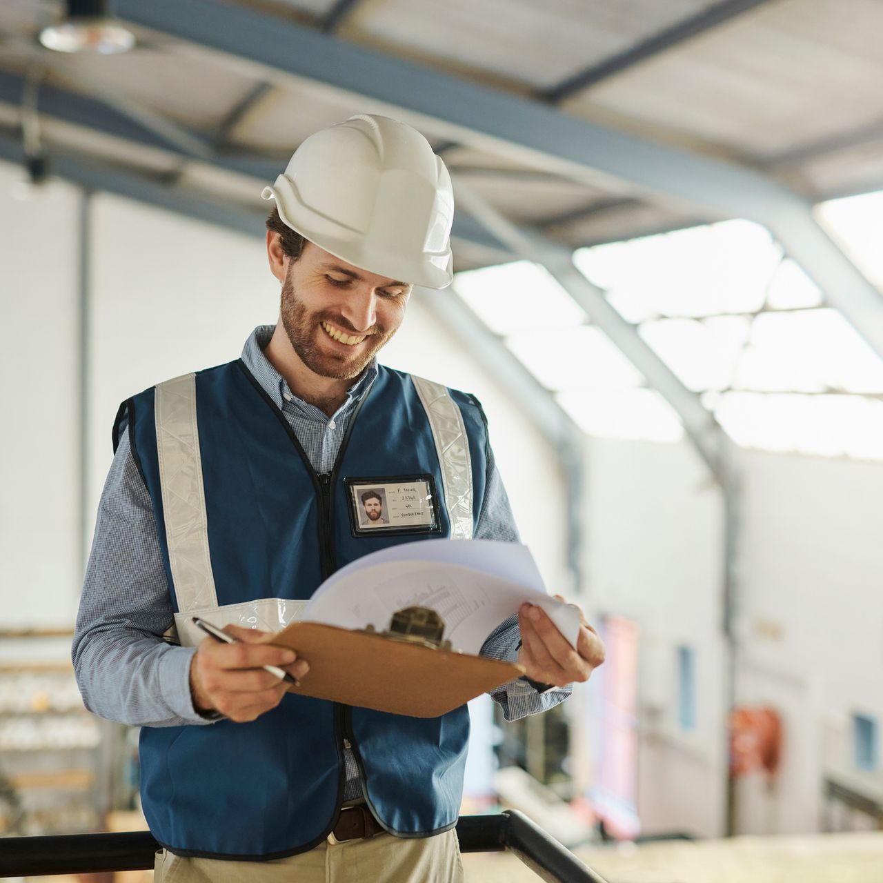 Worker in orange hard hat changing a ceiling light in a bright room
