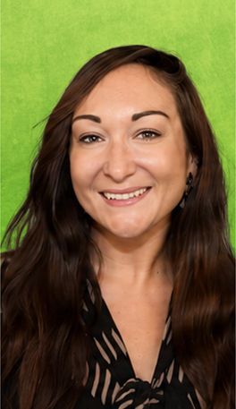 Woman with long, reddish-brown hair smiling, wearing a patterned blouse, set against a green background.