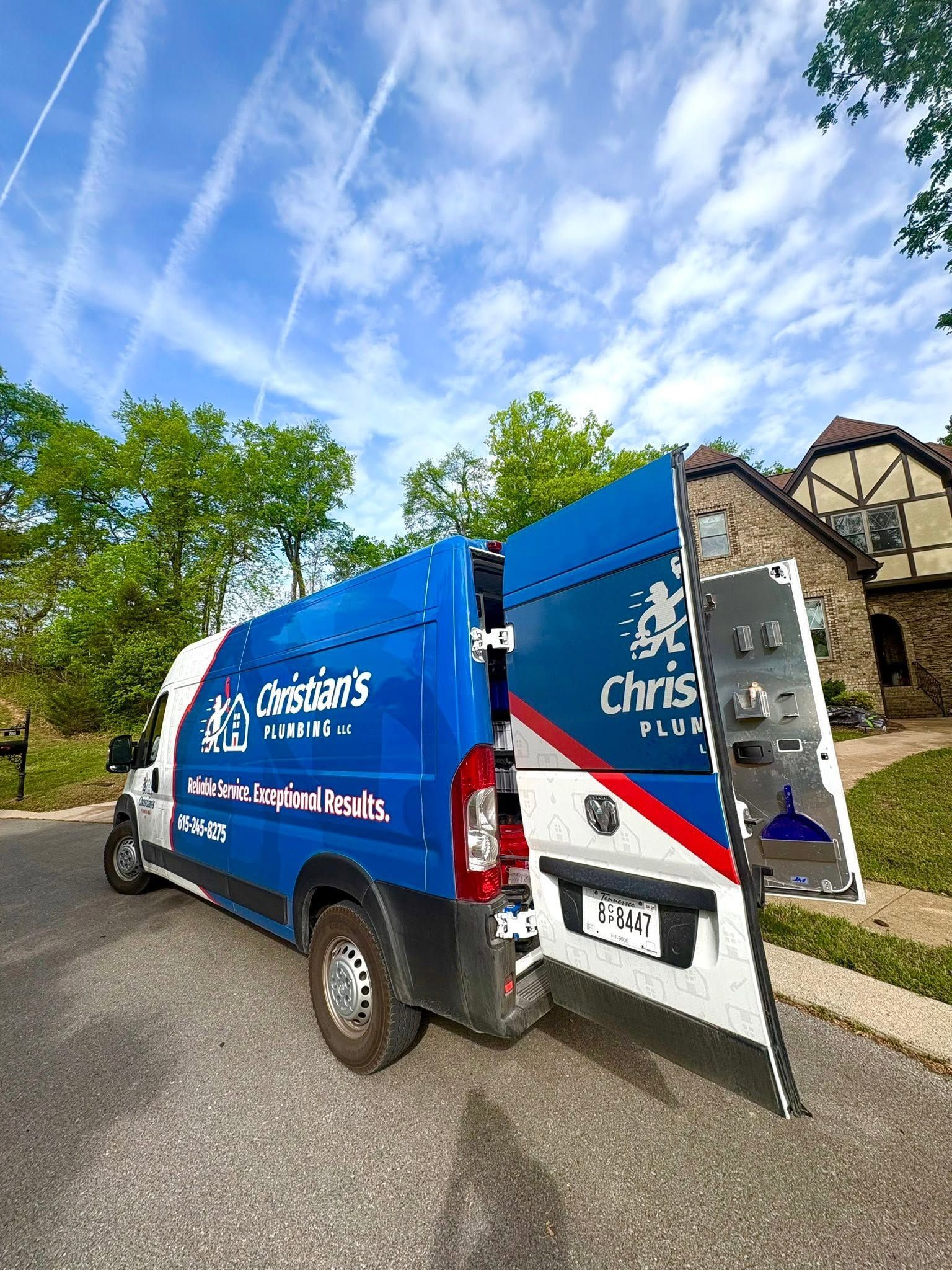 Blue charity van with open rear door parked on a street under a partly cloudy sky