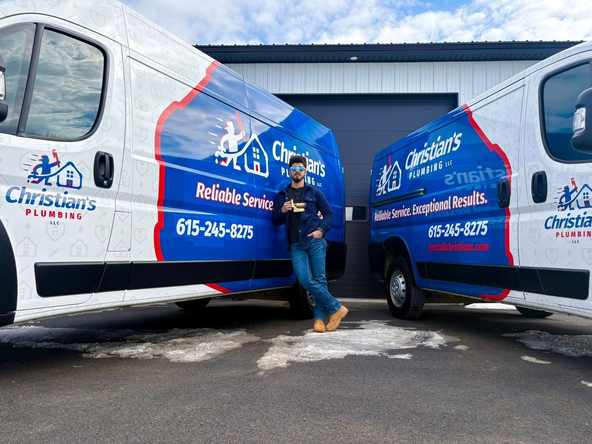 Person posing between two branded blue-and-white service vans outside a building
