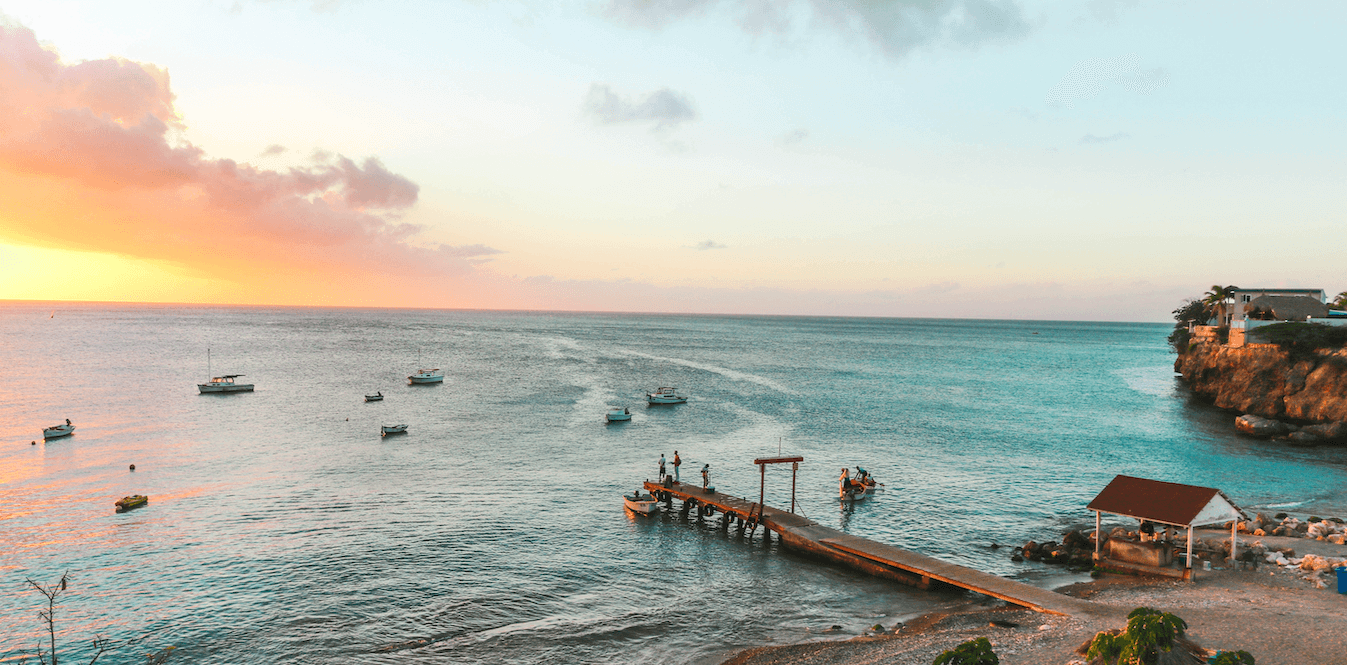 Una vista aérea de un muelle en medio del océano al atardecer.