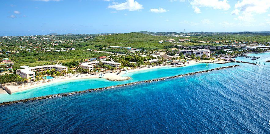 Una vista aérea de una playa tropical con un resort al fondo.
