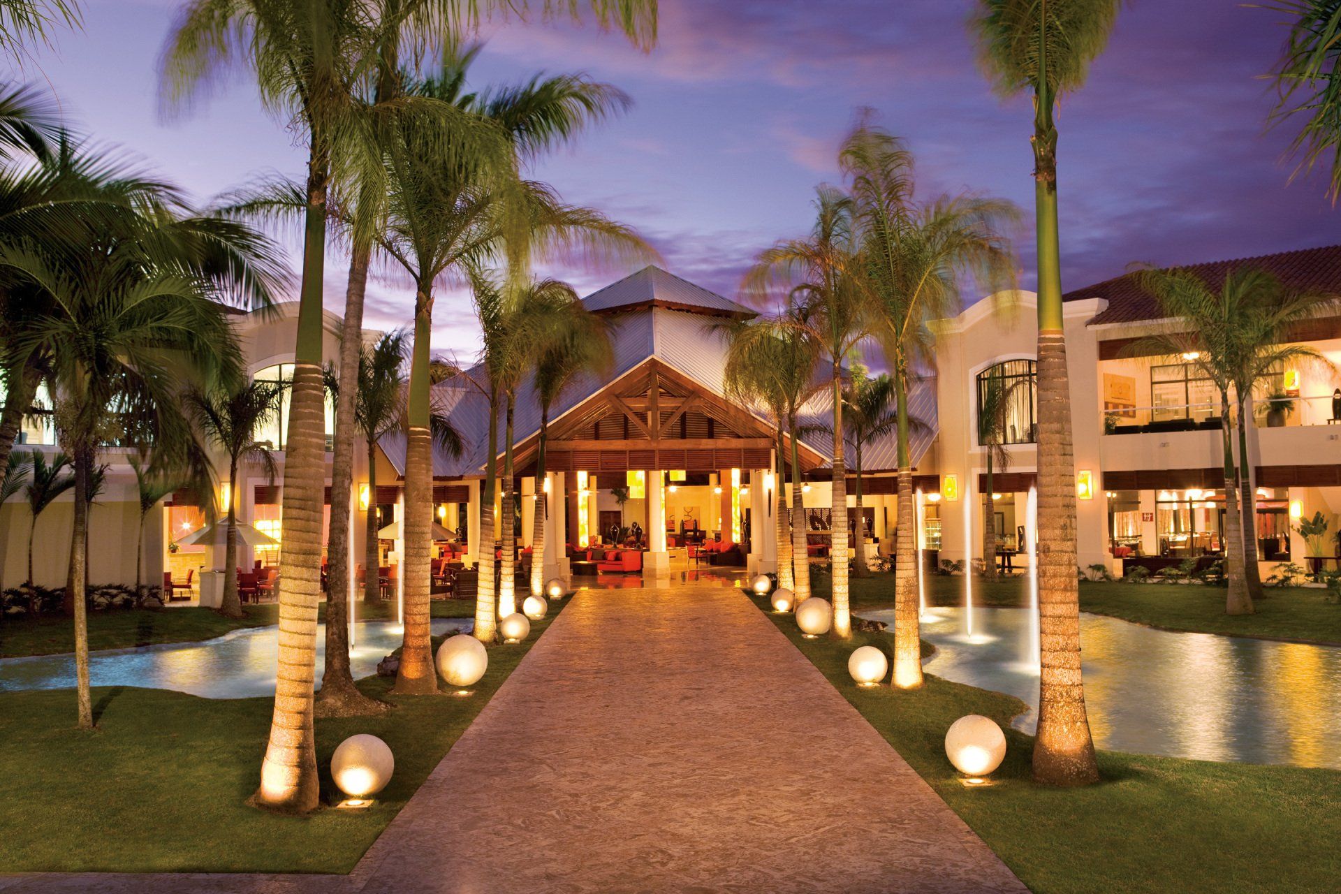Un hotel con palmeras y una pasarela que conduce a él