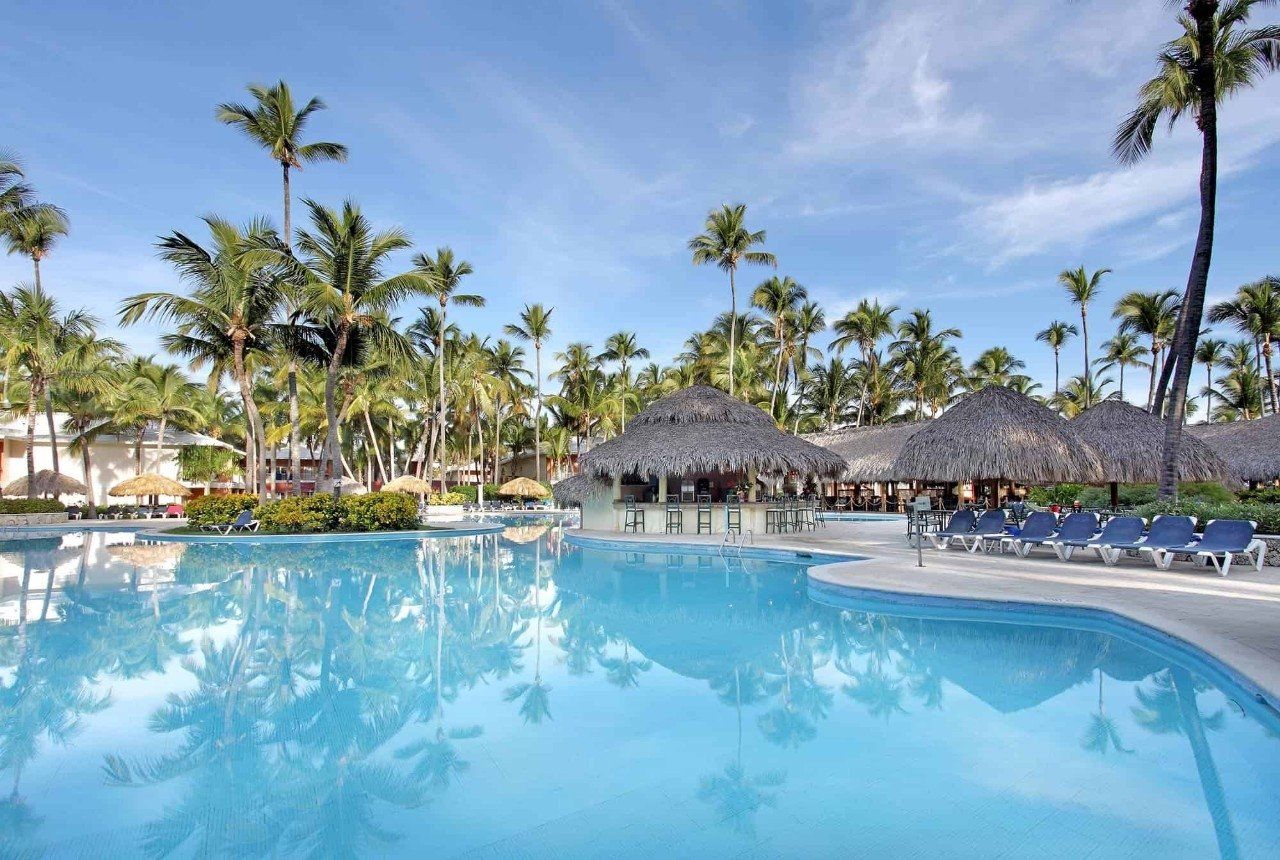 Una gran piscina rodeada de palmeras y sillas