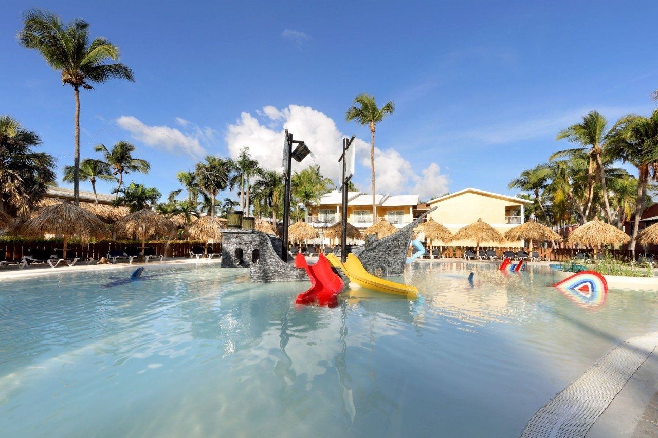 Una gran piscina rodeada de palmeras y sombrillas.