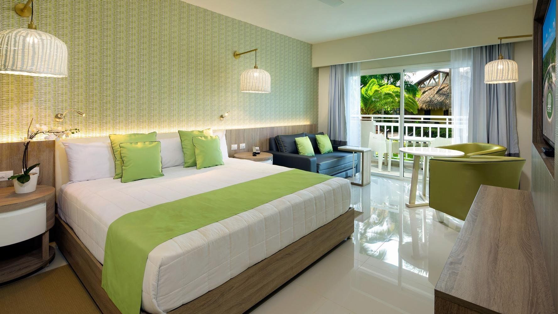 Una habitación de hotel con cama king size, sofá, mesa y televisor.