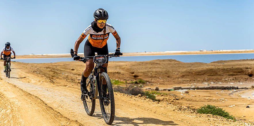 Una mujer anda en bicicleta por un camino de tierra.