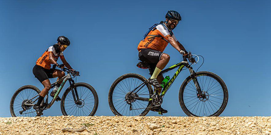Un hombre y una mujer andan en bicicleta por un camino de tierra.
