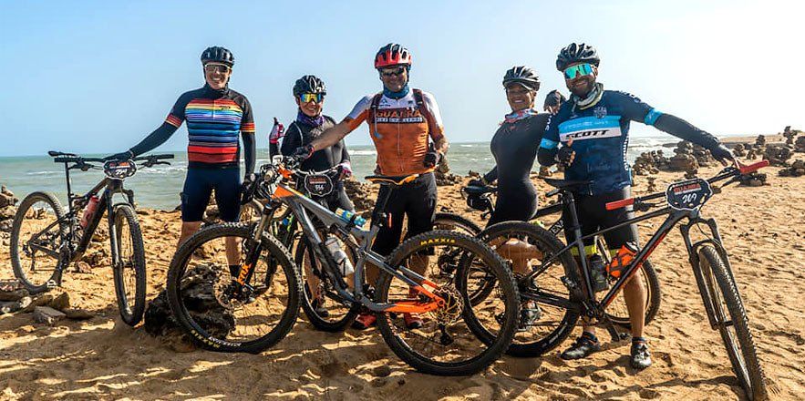 Un grupo de personas paradas junto a bicicletas en una playa.