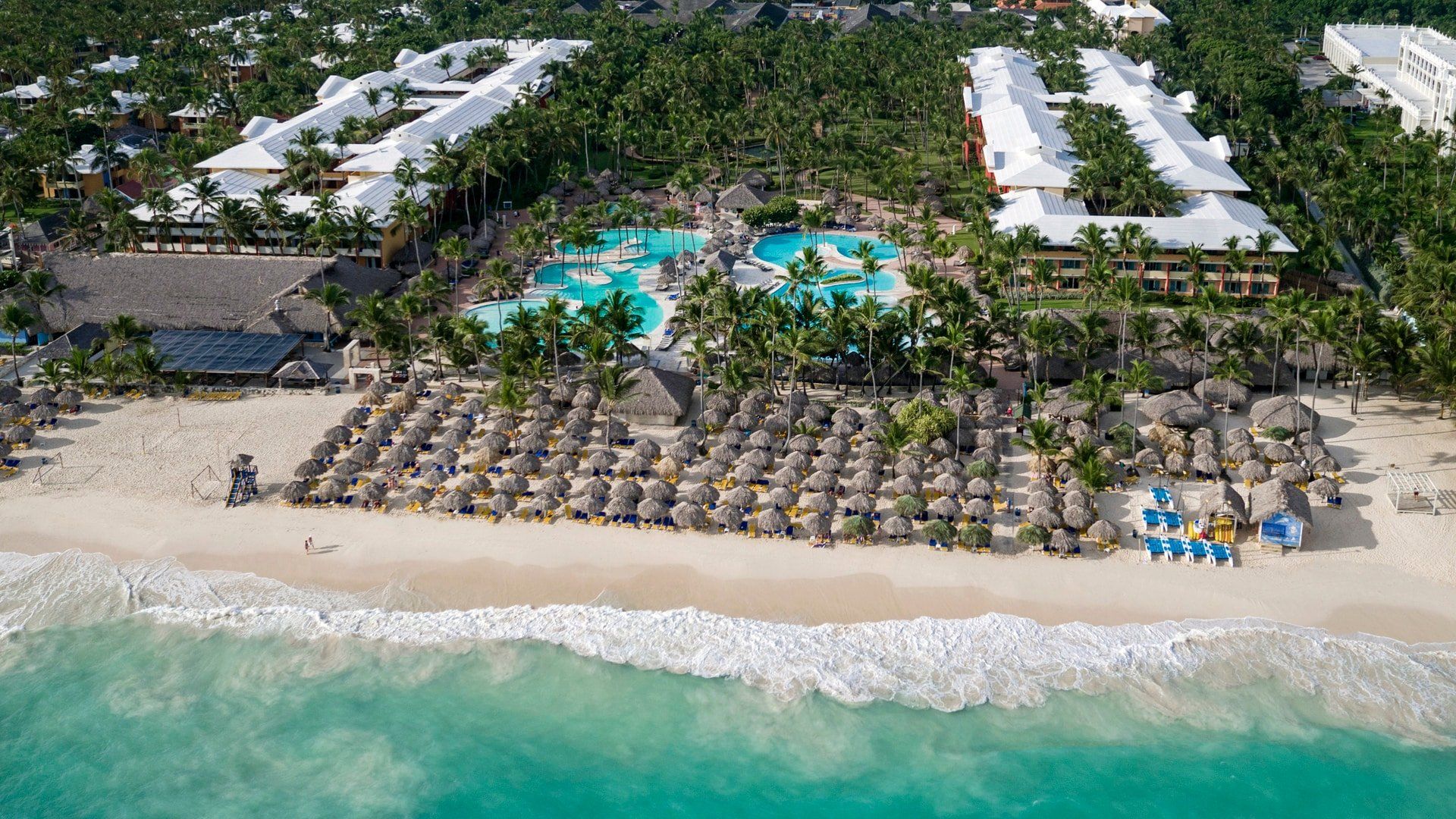 Una vista aérea de una playa con sombrillas y piscina.