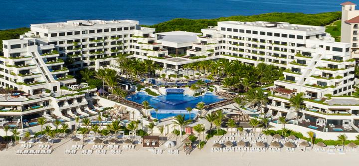Una vista aérea de un gran hotel con una gran piscina rodeada de palmeras.