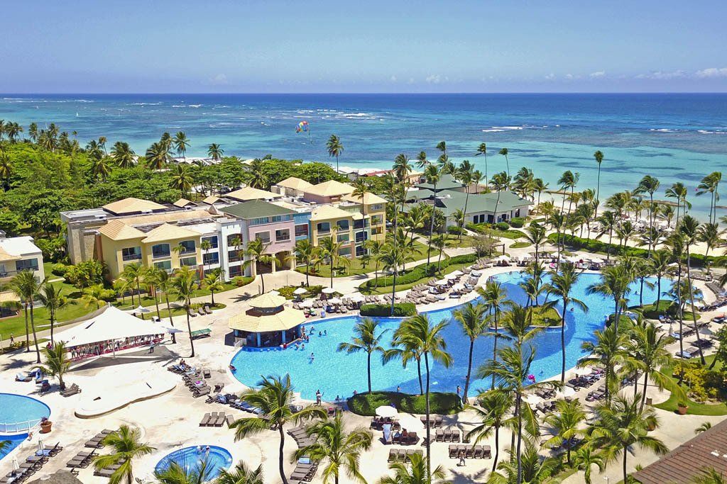 Una vista aérea de un resort tropical con una gran piscina rodeada de palmeras.