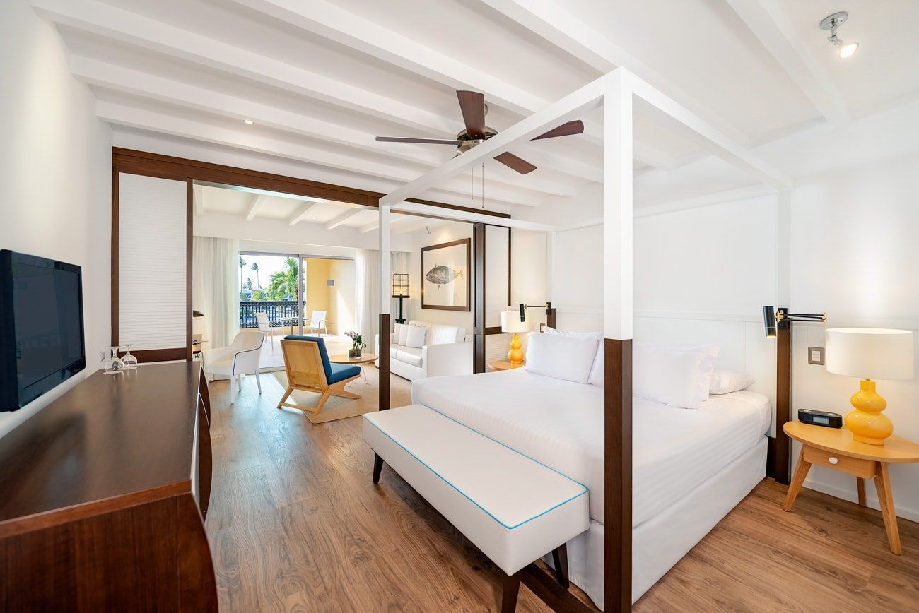 Una habitación de hotel con una cama con dosel y un ventilador de techo.