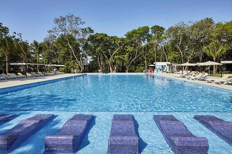 Una gran piscina rodeada de sillas y árboles.