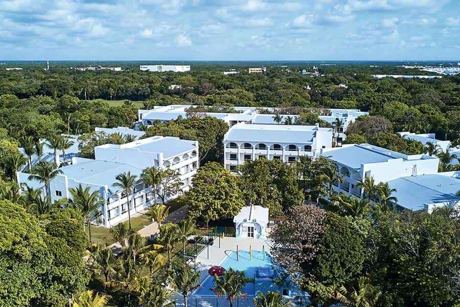 Una vista aérea de un hotel rodeado de árboles y palmeras.