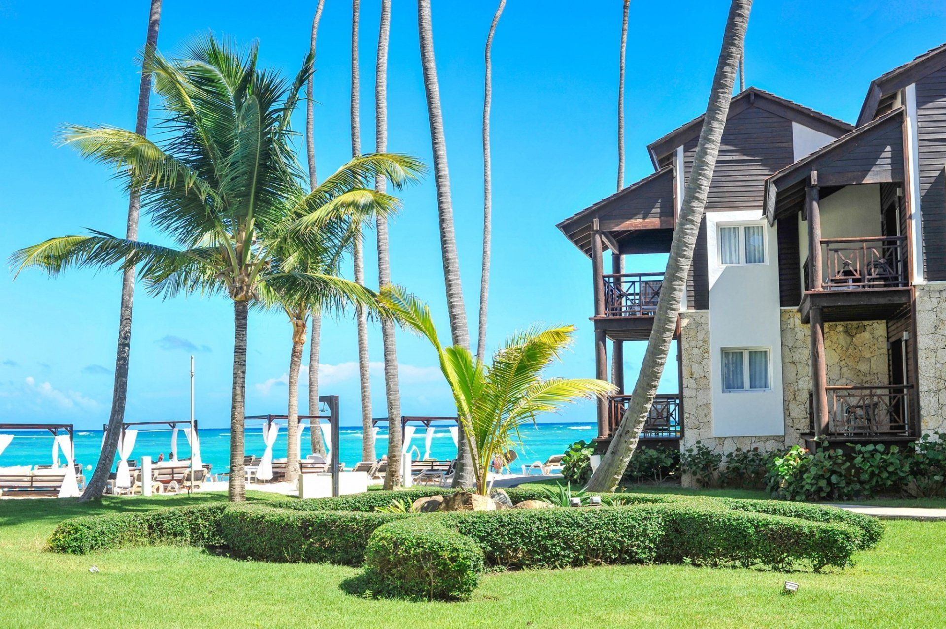 Un hotel con palmeras al frente y vista al mar.