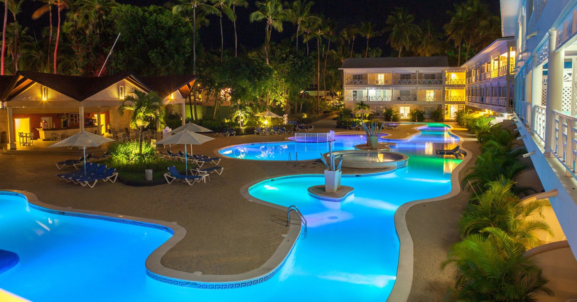 Una gran piscina se ilumina por la noche en un resort.