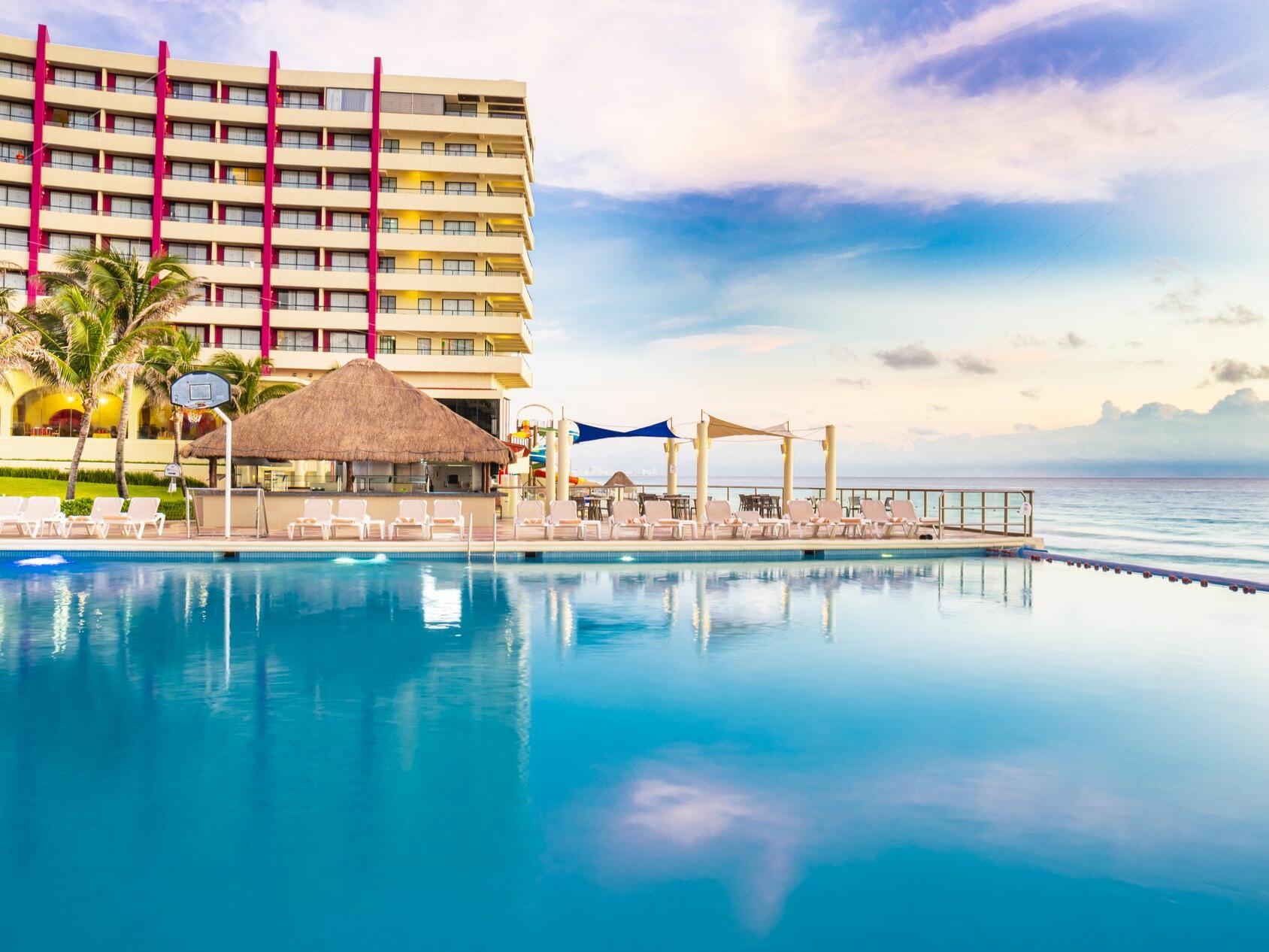 Hay una gran piscina frente a un hotel.