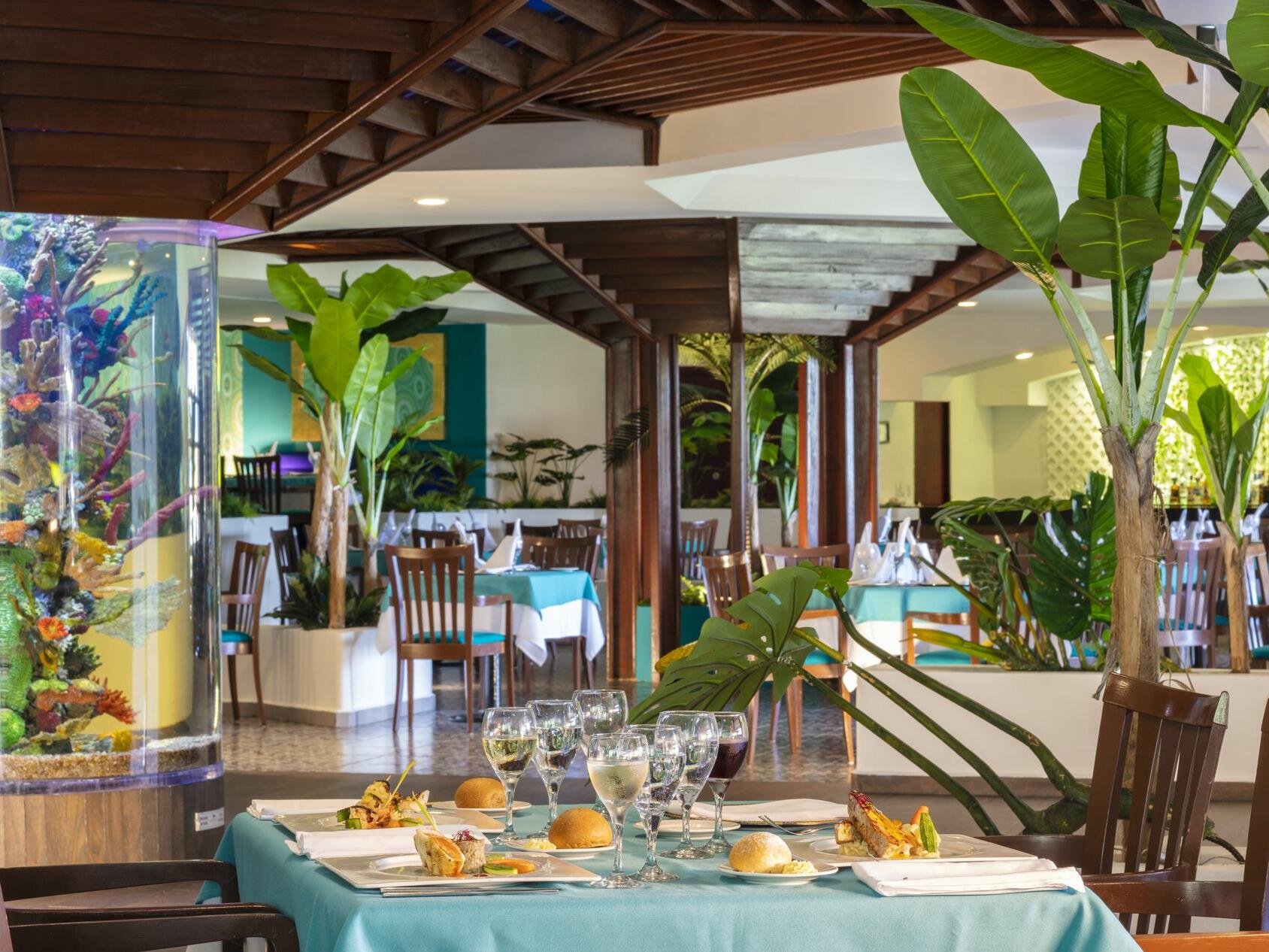 Un restaurante con mesas y sillas y una pecera al fondo.