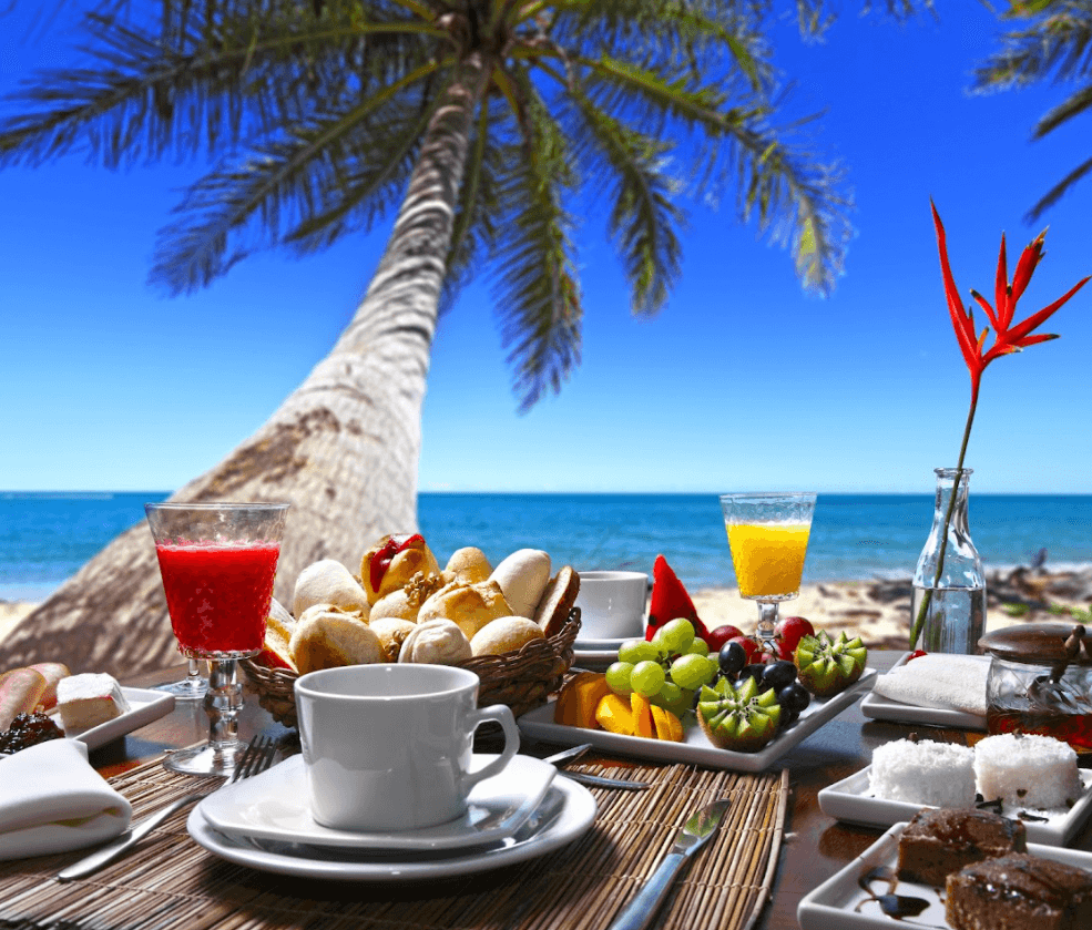 Una mesa con comida y bebidas con una palmera al fondo