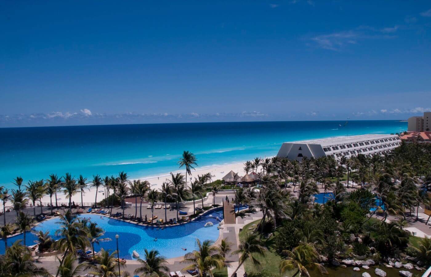 Una vista aérea de un resort tropical con una gran piscina y una playa.