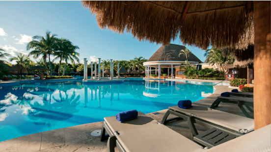 Una gran piscina rodeada de sillas y sombrillas en un resort.