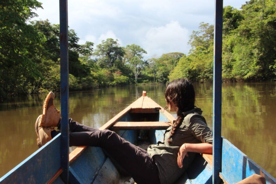 Una mujer está tumbada en un barco en un río.