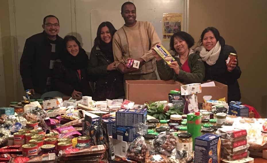 A group of people are standing around a table filled with food.