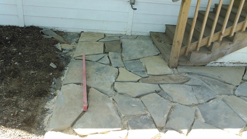 A red ruler is laying on a stone walkway next to stairs