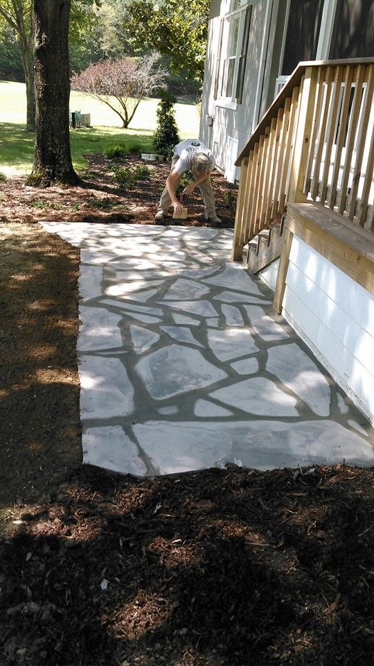 A man is working on a stone walkway next to a house.