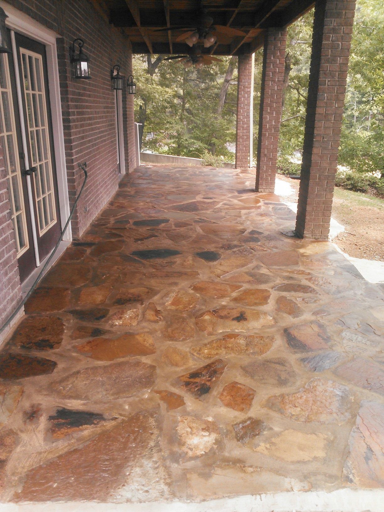 A stone porch with a brick building in the background