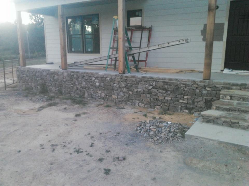 A stone wall is being built in front of a house.