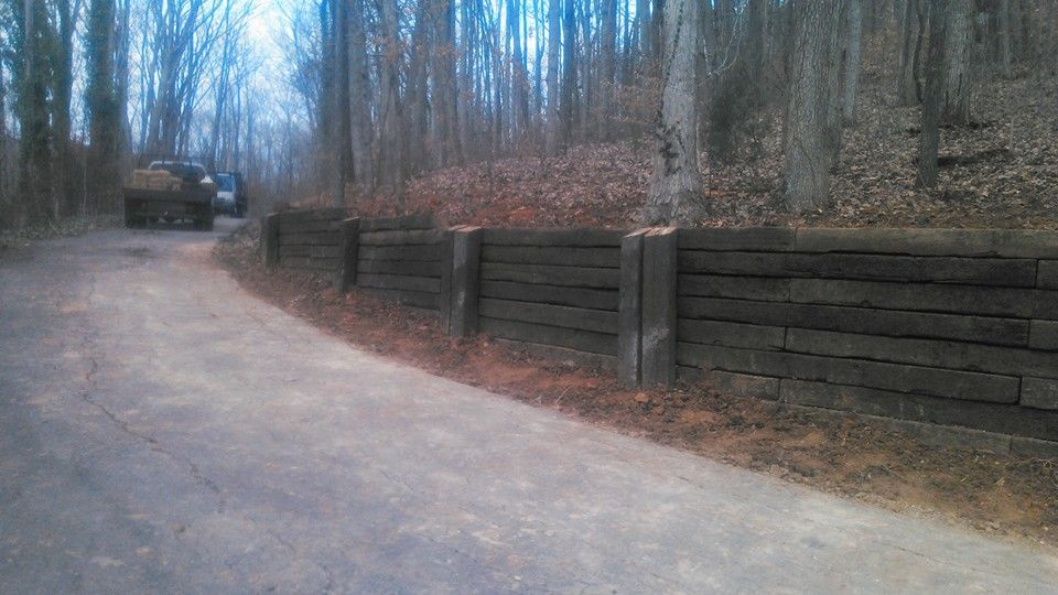A truck is driving down a dirt road next to a wooden fence.