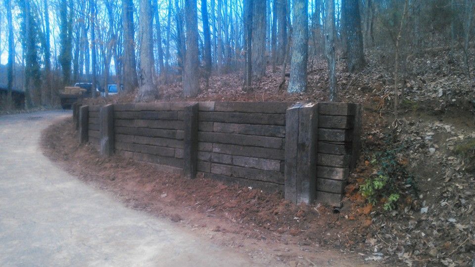 A wooden fence along the side of a dirt road in the woods.