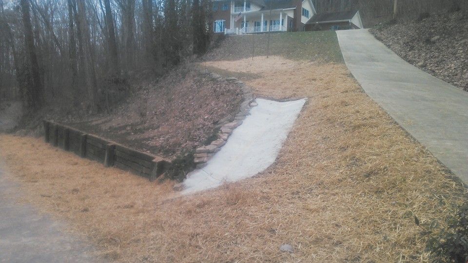 A concrete walkway going down a hill next to a house.