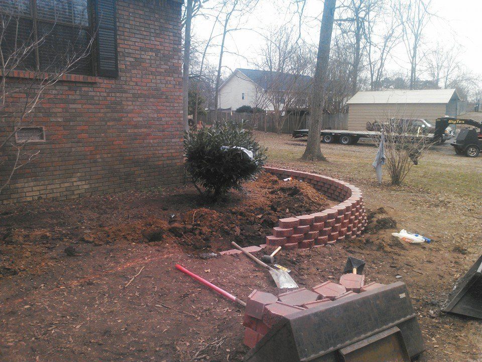A brick wall is being built in the backyard of a house.