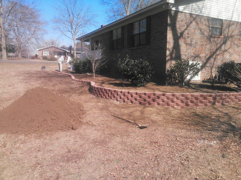 A brick wall is being built in front of a house.