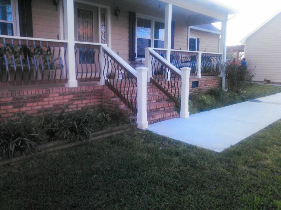 A house with a porch and stairs and a sidewalk in front of it.