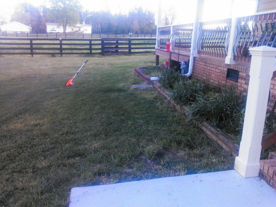 A lawn mower is sitting in the grass in front of a house
