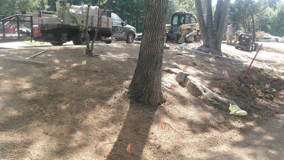A truck is parked in the dirt next to a tree.