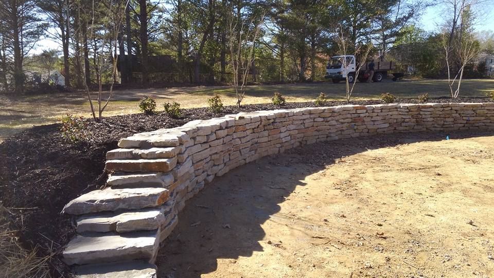A stone wall with stairs leading up to it in a yard.