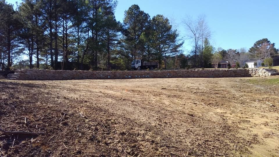 A large dirt field with trees in the background