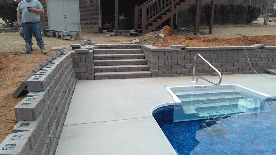 A man is standing next to a swimming pool under construction.