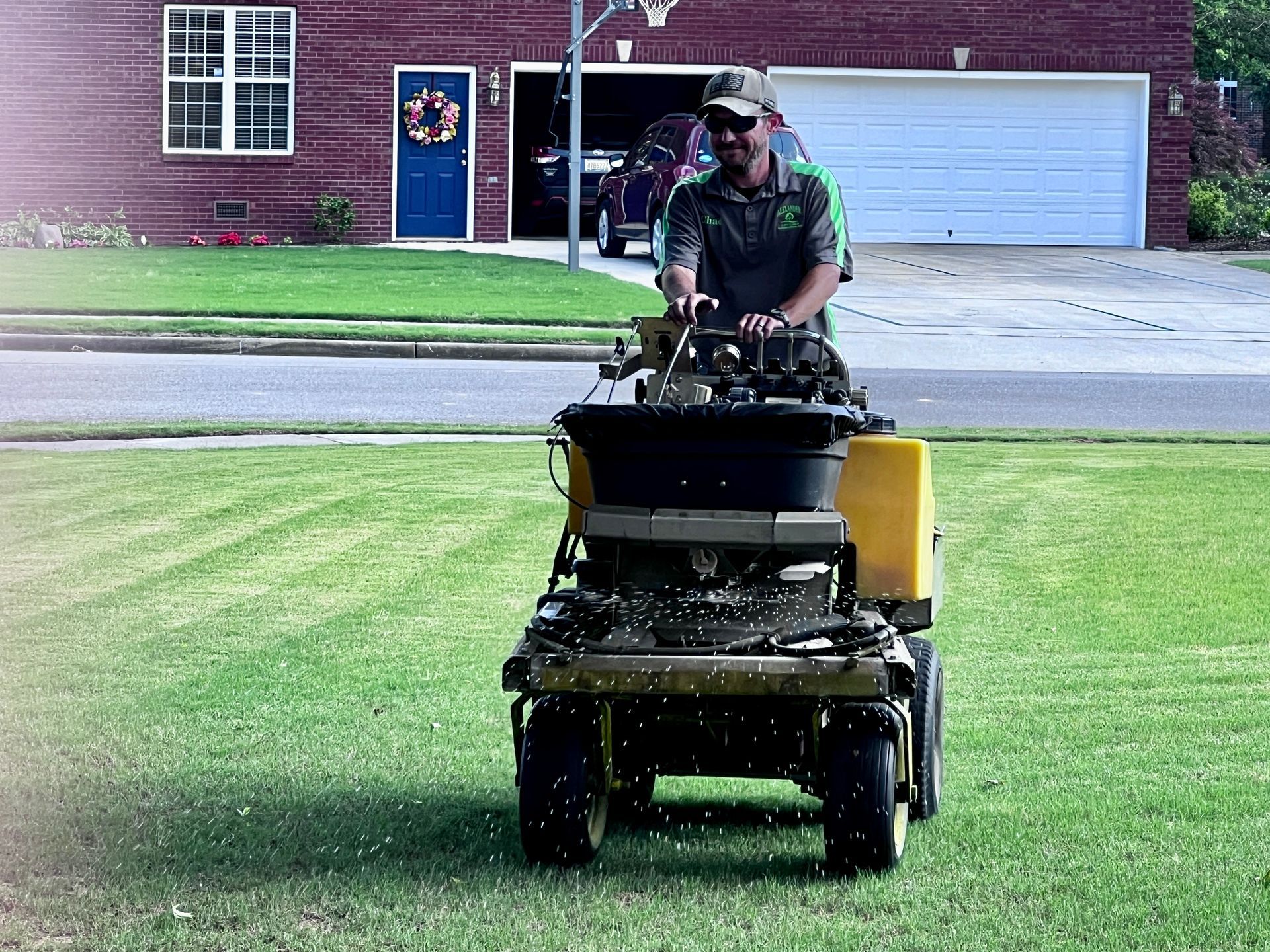 A man is riding a lawn mower on a lush green lawn.